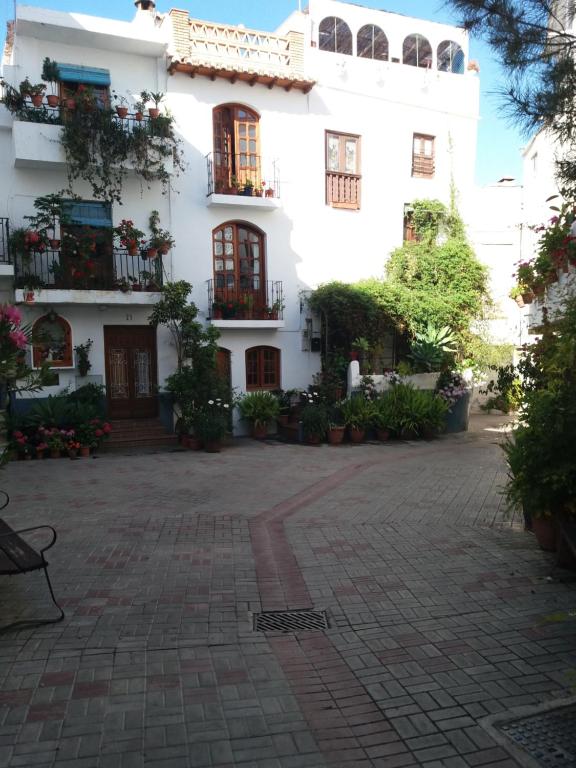 un edificio blanco con ventanas y plantas en un patio en Casa Santa Ana, en Lanjarón
