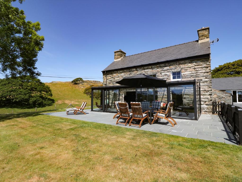 a house with a patio with chairs and an umbrella at Garth Morthin The Farmhouse in Porthmadog