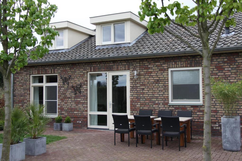 een patio met een tafel en stoelen voor een bakstenen huis bij Vakantiewoning Pardoes in Hegelsom