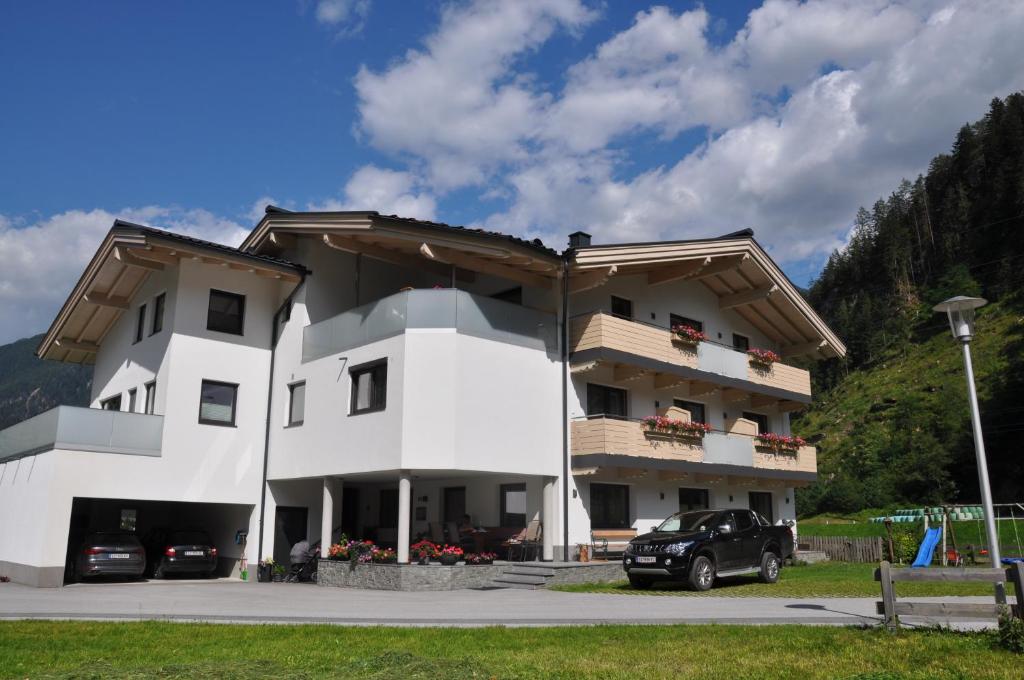 un edificio blanco con coches estacionados frente a él en Gästehaus Holaus en Mayrhofen