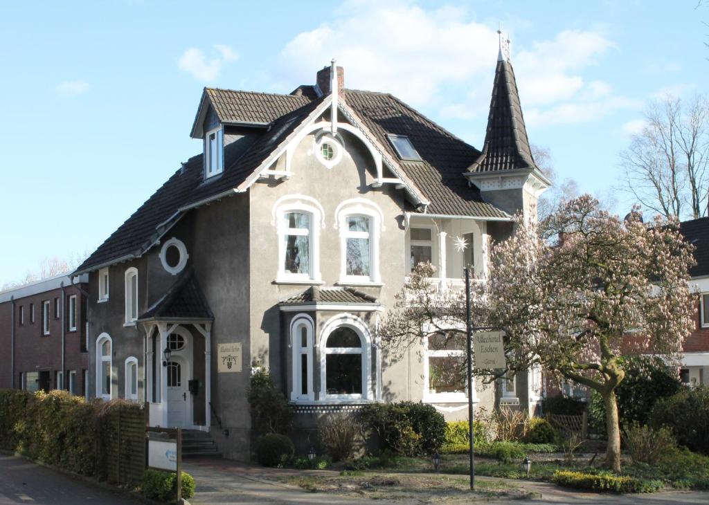 a large house with a turret on a street at Alleehotel-Eschen in Aurich
