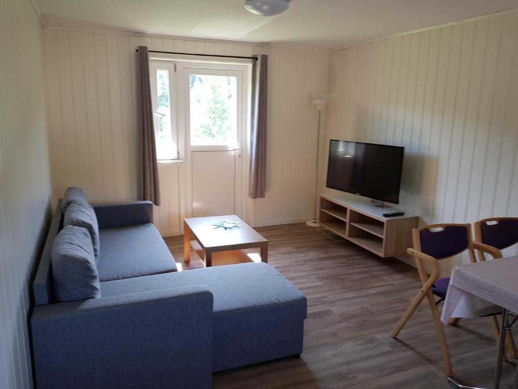 sala de estar con sofá azul y TV en Bech's Hotell & Camping, en Mo i Rana