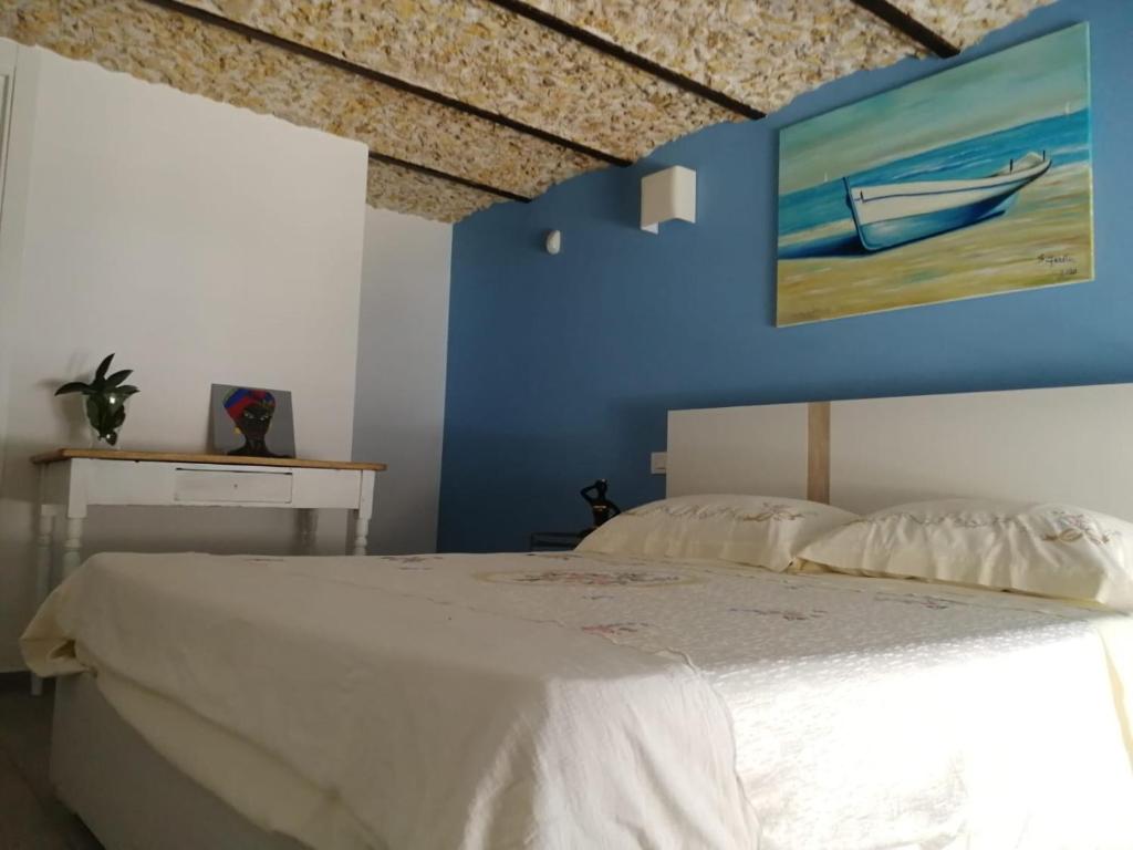 una camera con un letto bianco e una parete blu di A casa di Ninuccia a Siracusa