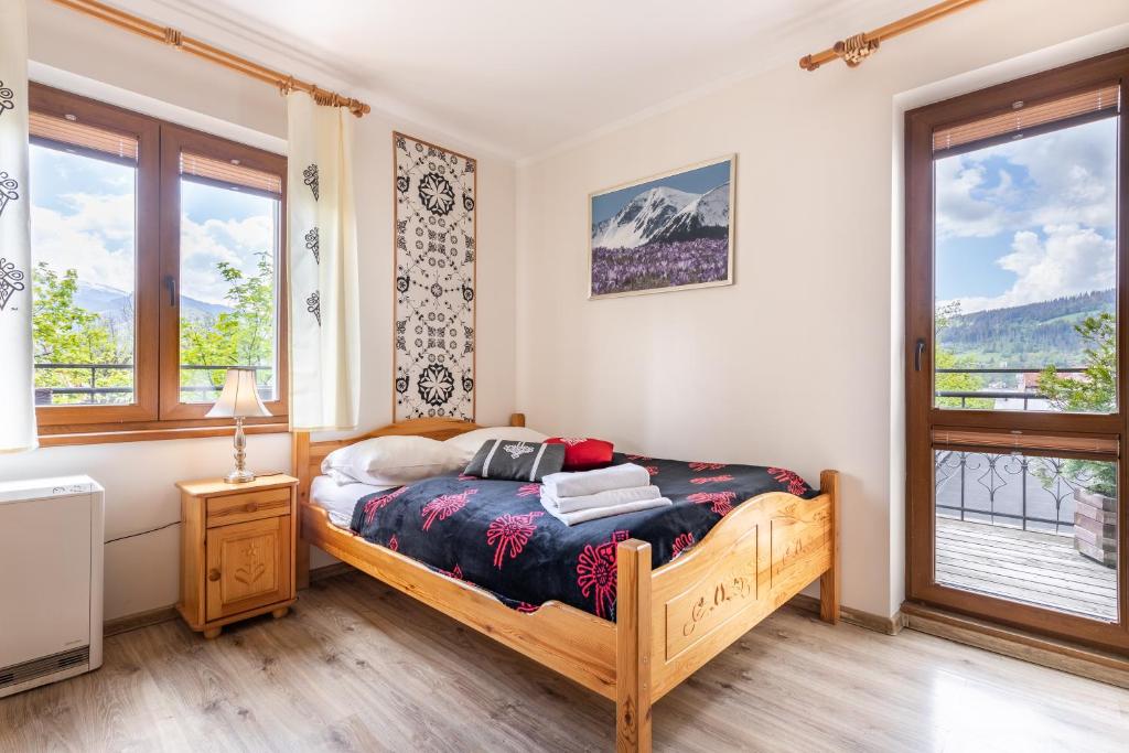 a bedroom with a bed and two windows at Apartamenty Zakopane Krupówki in Zakopane
