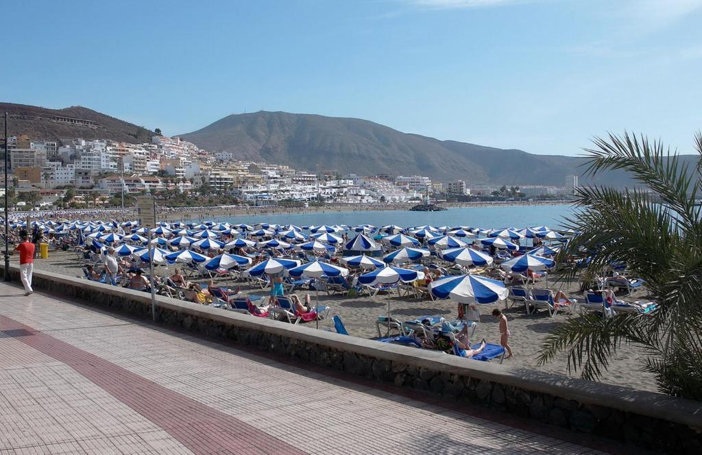 a bunch of umbrellas and people sitting on the beach at Apartments in Los Cristianos Centre in Los Cristianos