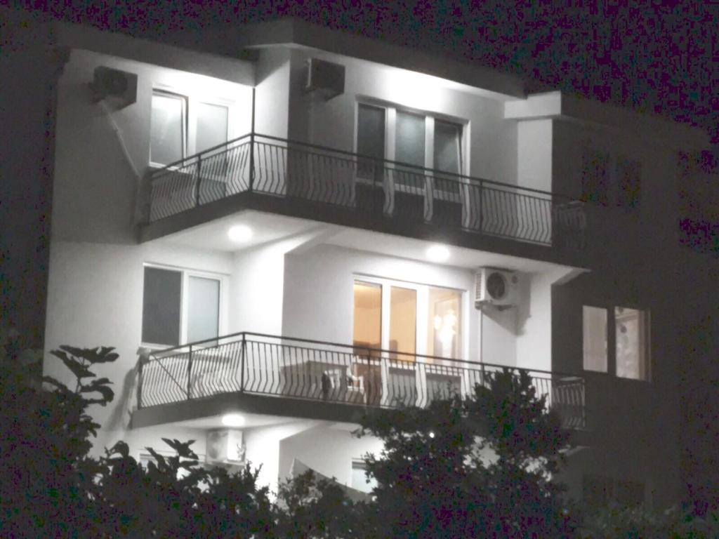 a large white building with balconies and lights on it at Kasneci Apartments in Ulcinj