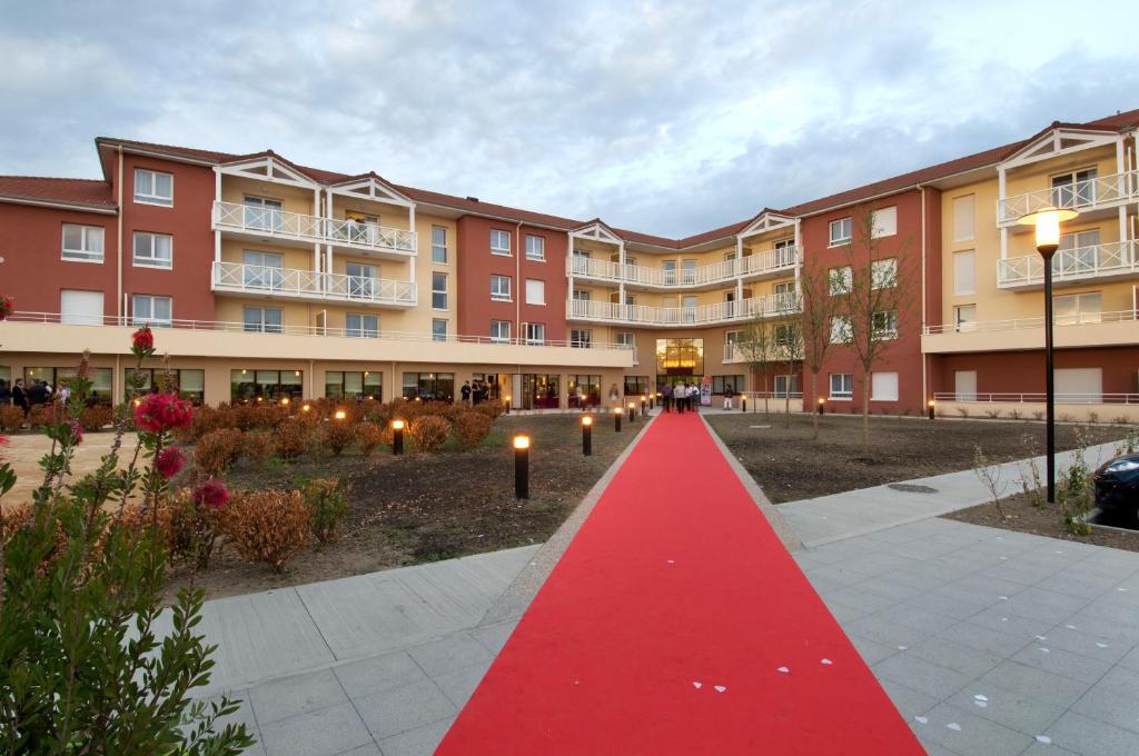 un chemin de tapis rouge devant un bâtiment dans l'établissement Domitys Le Parc Saint Germain, à Montrond-les-Bains