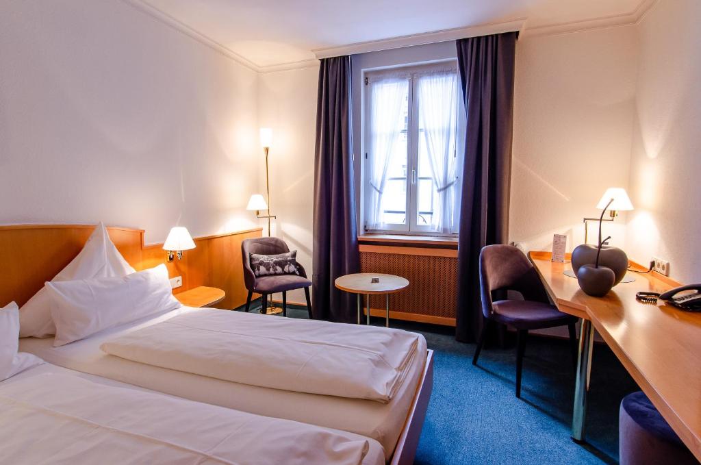 a hotel room with a bed and a desk and a window at Hotel Gasthof Hecht in Wolfach