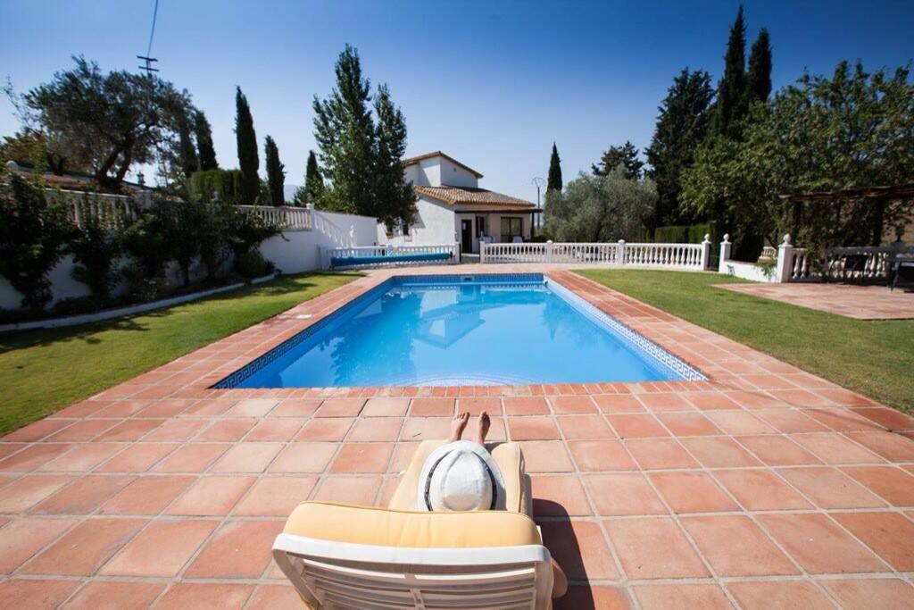 uma piscina com uma cadeira ao lado de uma casa em Finca Los Abetos em Villanueva del Rosario