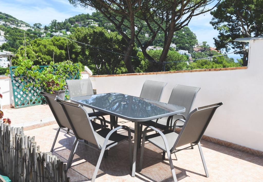 un tavolo in vetro e sedie su un patio di Ai due leoni a Capri