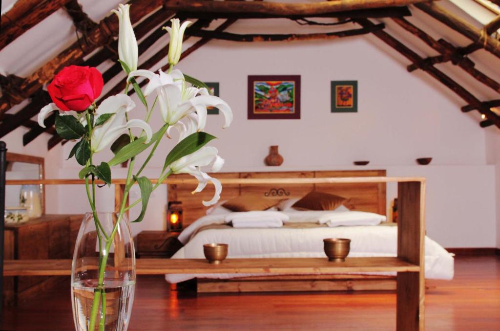 un jarrón lleno de flores sobre una mesa en un dormitorio en Patio de Piedra Hotel Boutique, en La Paz