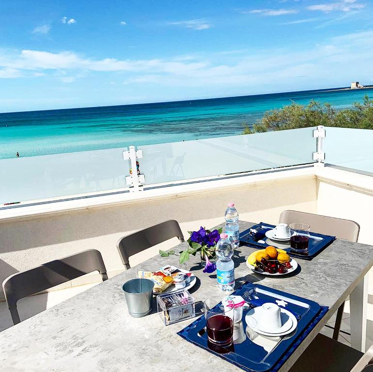 una mesa con comida en la parte superior de un balcón con vistas al océano en Baia Azzurra B&B en Torre Lapillo