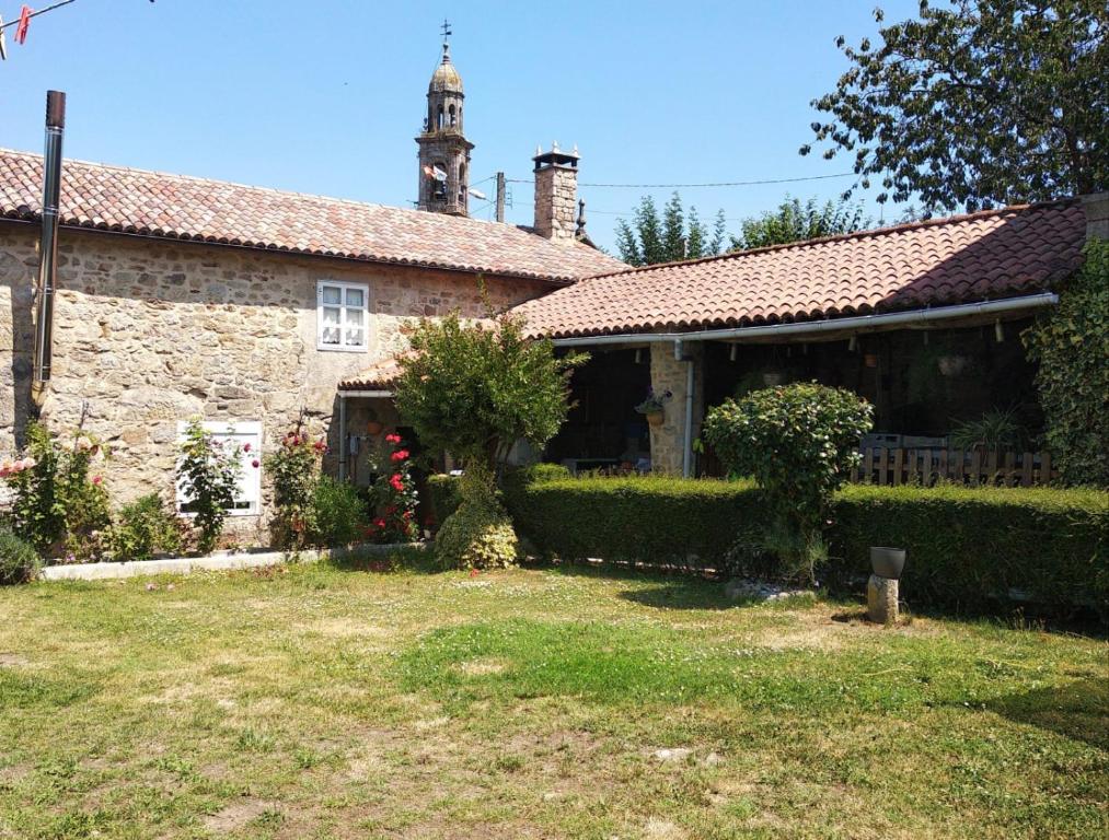 una vieja casa de piedra con una torre de reloj en un patio en Casa Cabaleira, en Silleda