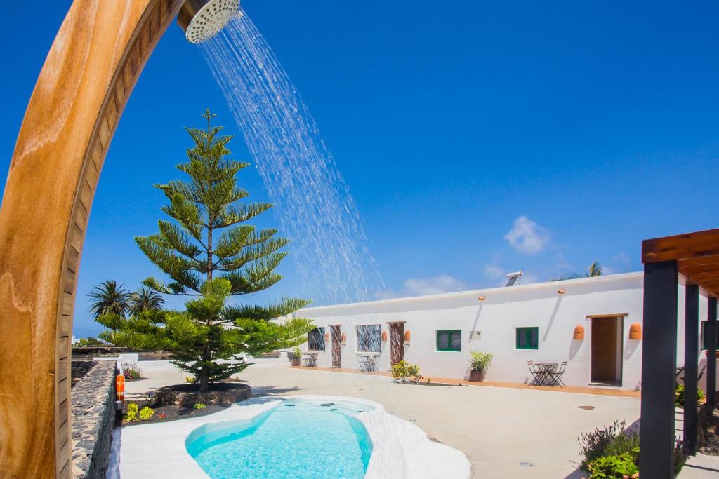 vistas a un edificio con un árbol y una piscina en Casa Volcán y Mar, en Yaiza