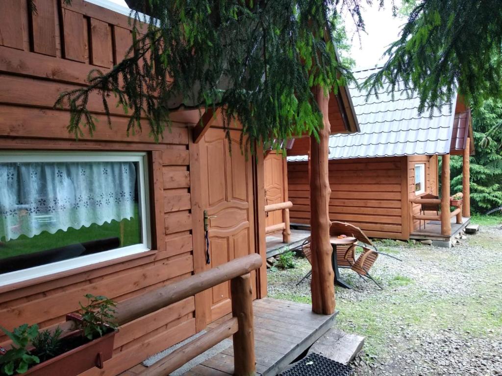 eine Blockhütte mit einer Veranda und einem Baum in der Unterkunft Domki Goralskie przy karczmie Szlachtowskiej in Szlachtowa