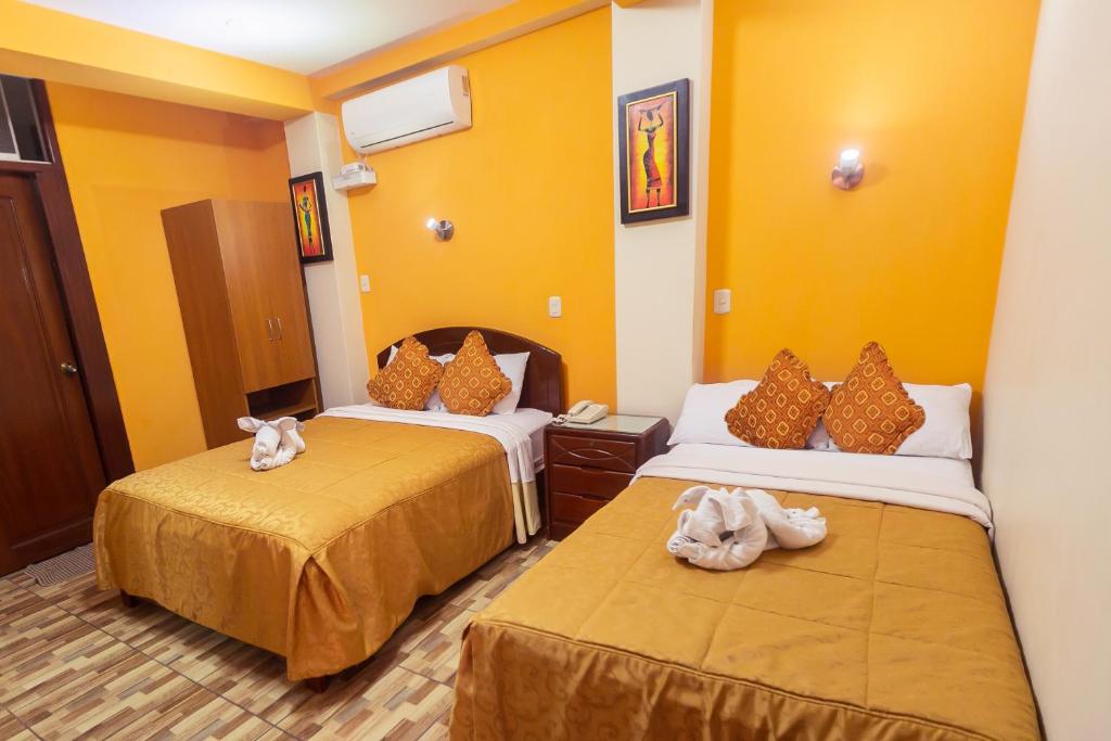 2 camas en una habitación con paredes amarillas en Hotel Suite Plaza, en Trujillo