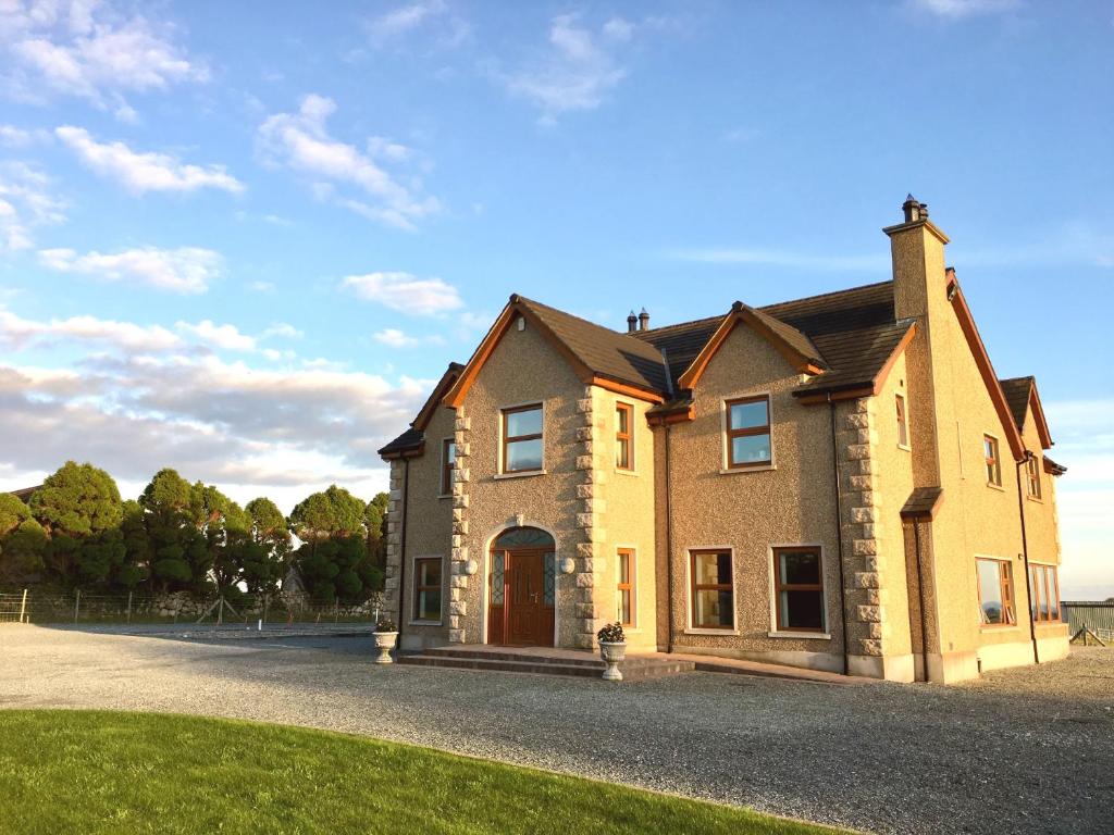 a large brick house on a gravel driveway at Mourne Country House Bed and Breakfast in Kilkeel