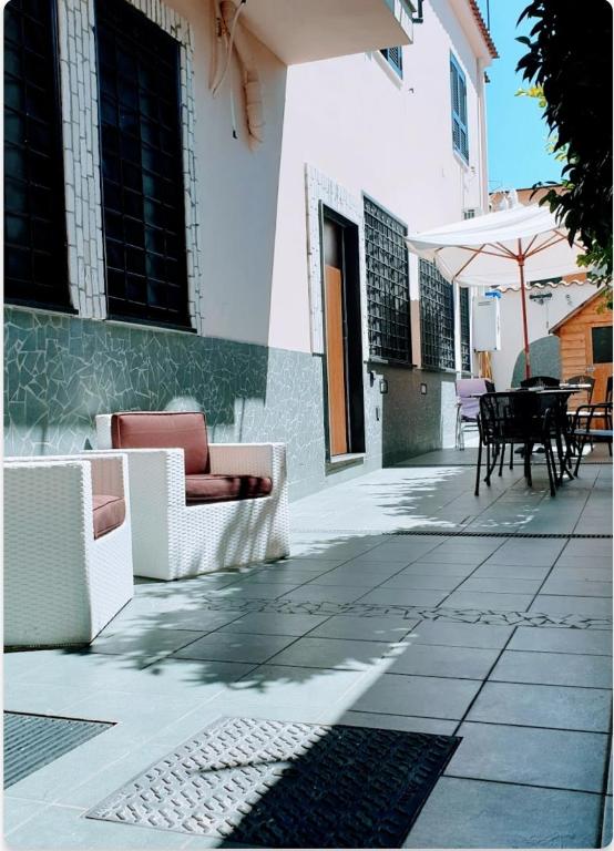 patio z kanapami, stołem i parasolem w obiekcie Casa Ary w mieście Frattamaggiore