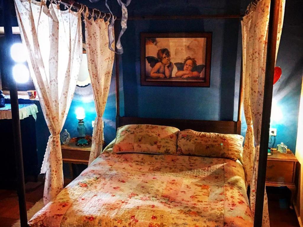 1 dormitorio con cama con dosel y una pintura en la pared en Rural house La Quinta de Maluromantic Hotel in Cuenca, en Valeria