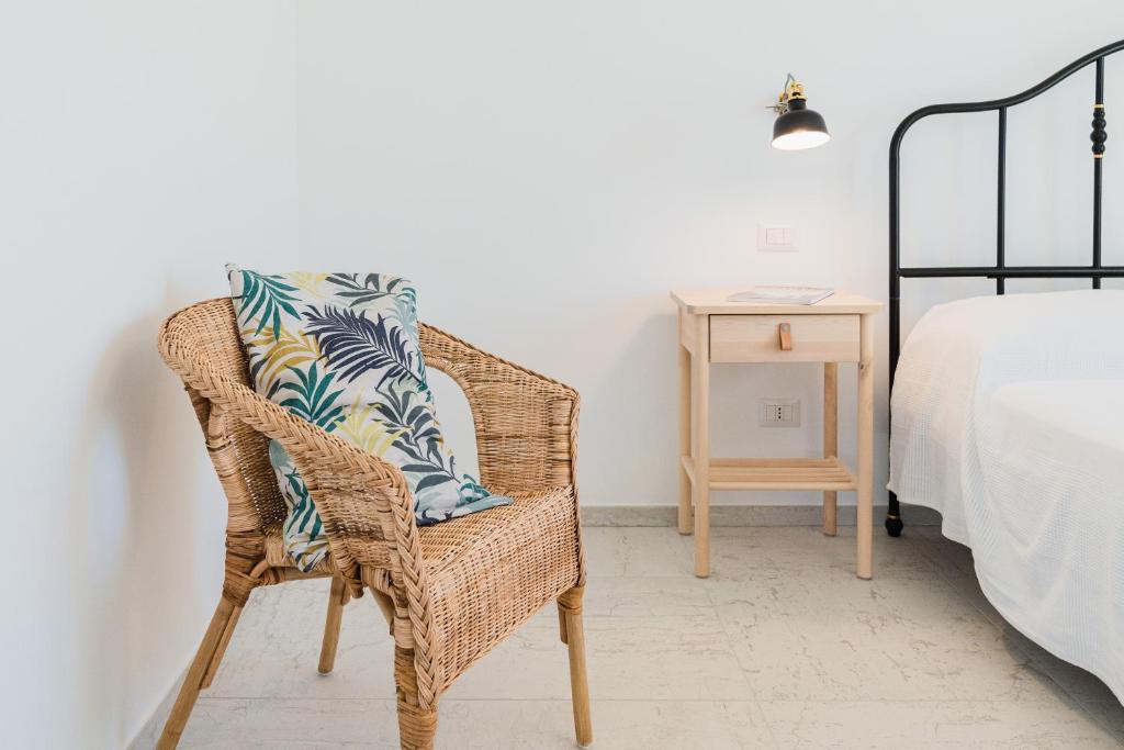 uma cadeira de vime com uma almofada ao lado de uma cama em Casa Palanca Camere em Sirolo
