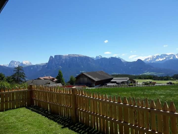 una valla en un campo con montañas en el fondo en Oberpfaffstallerhof, en Collalbo