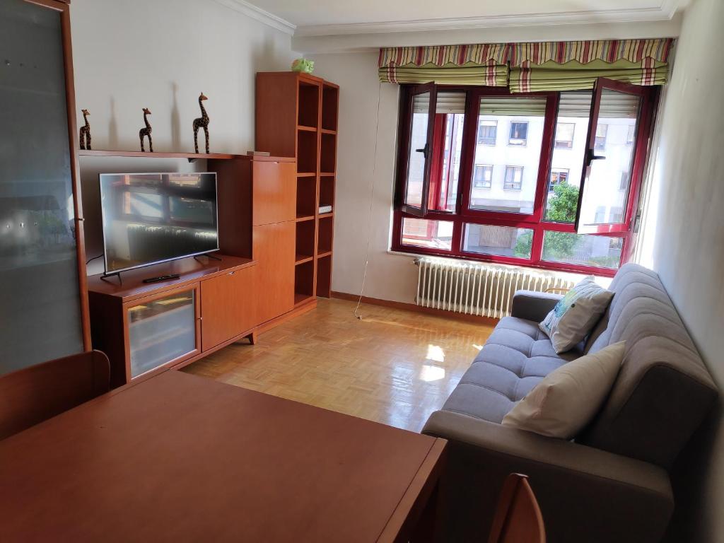 Amplio apartamento con todas las comodidades en Oviedo في أوفِييذو: غرفة معيشة مع أريكة وتلفزيون