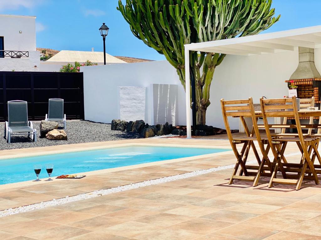 einen Pool mit zwei Stühlen, einem Tisch und zwei Weingläsern in der Unterkunft Canaryislandshost l My Nest in Nazaret