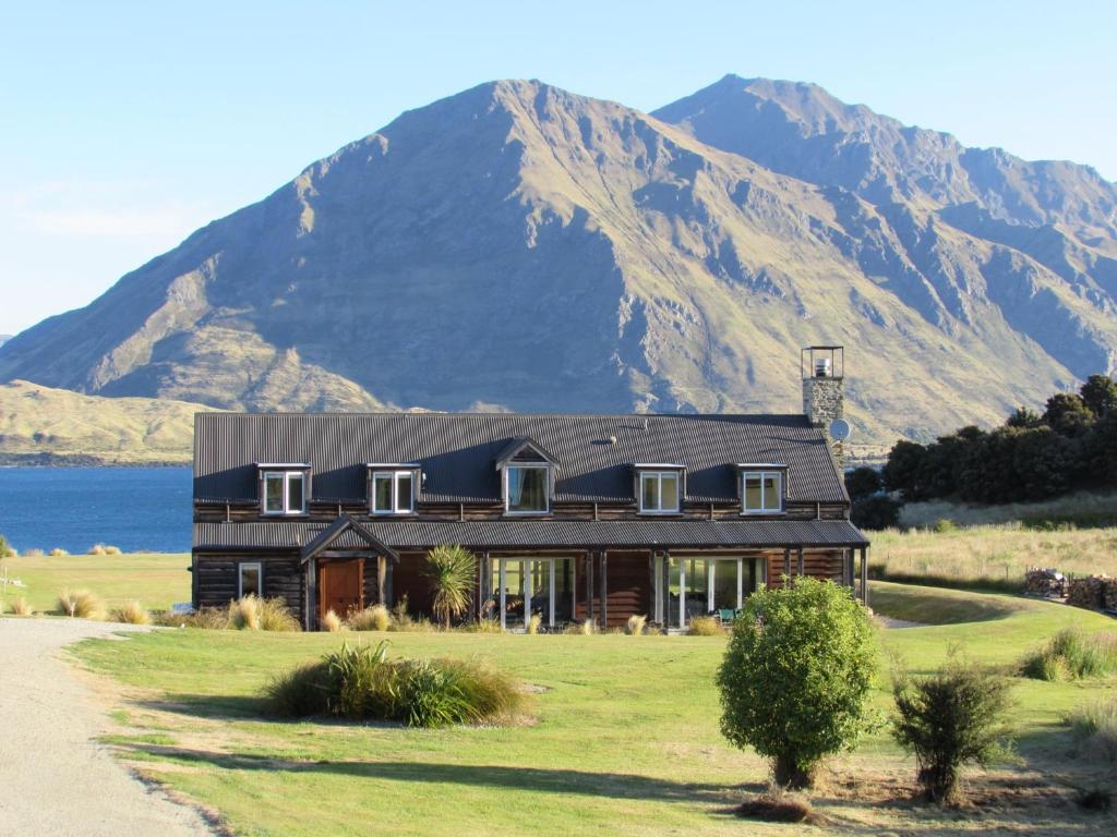 a house on a field with a mountain in the background at Buchanan Lodge - 60 acres on Wanaka lakefront in Wanaka
