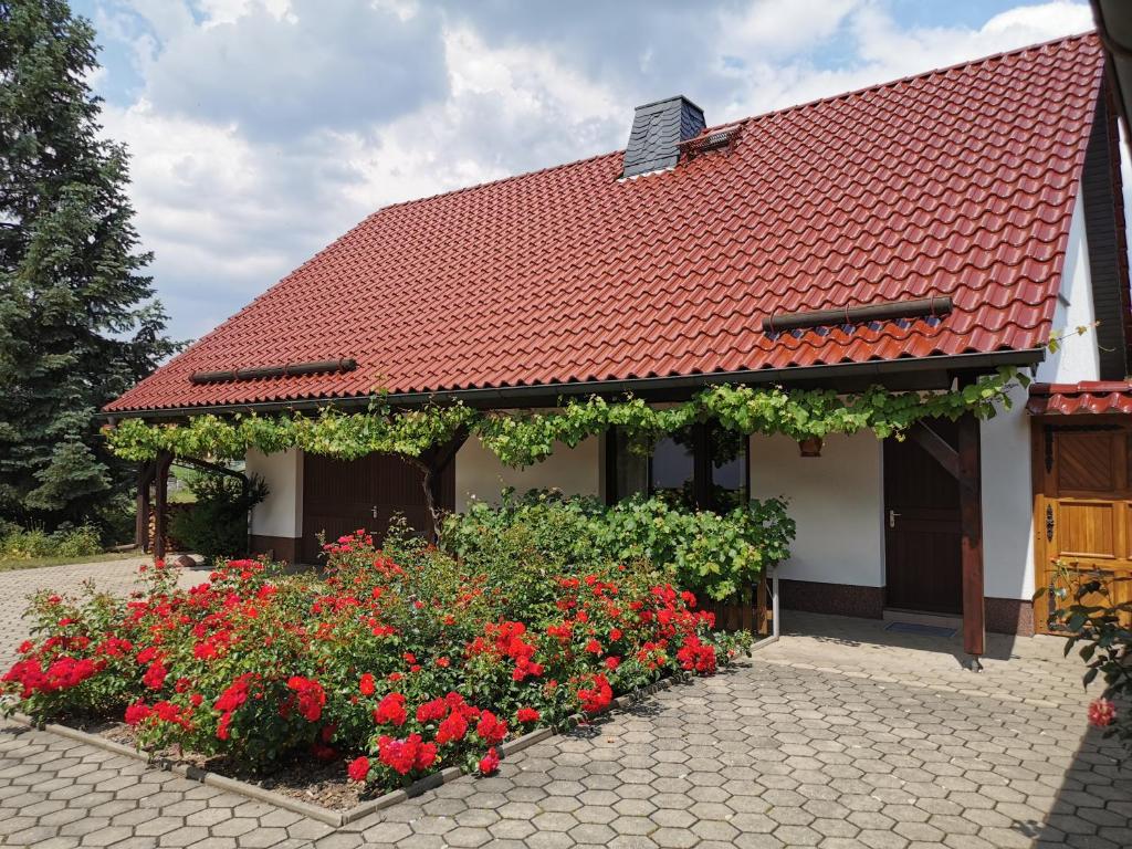 un edificio con techo rojo y algunas flores en Ferienhaus Rosenhof, en Glaubitz