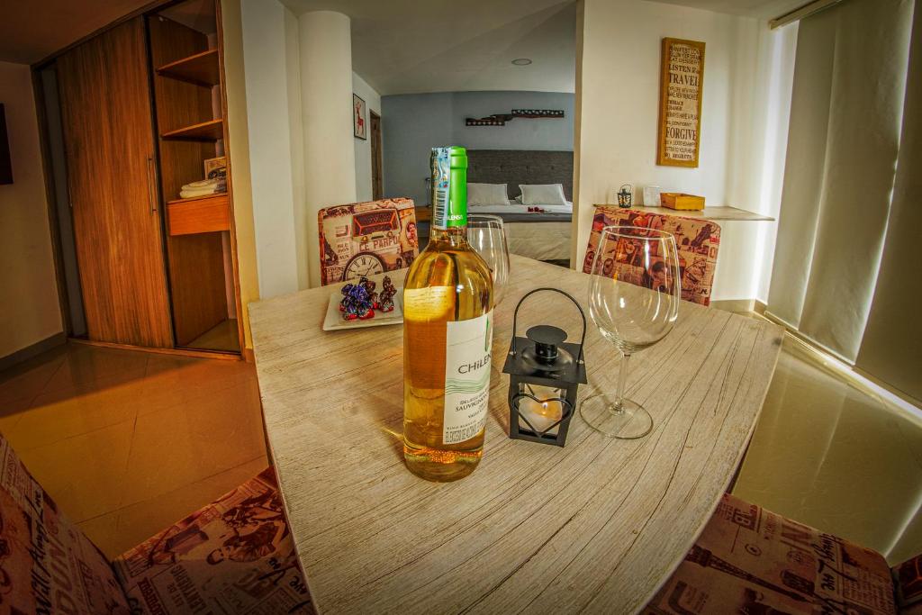 Hotel Llanogrande Airport في ريونيغرو: زجاجة من النبيذ على طاولة خشبية مع أكواب