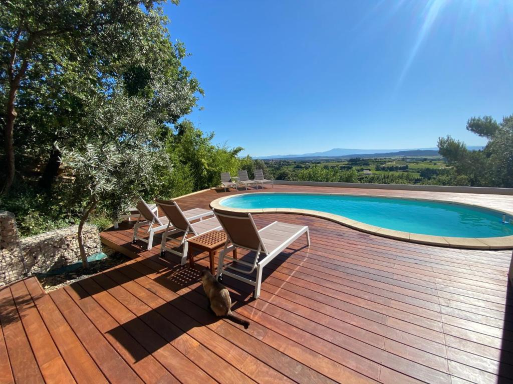 une terrasse en bois avec des chaises et une piscine dans l'établissement L’oustau, à Rochefort-du-Gard