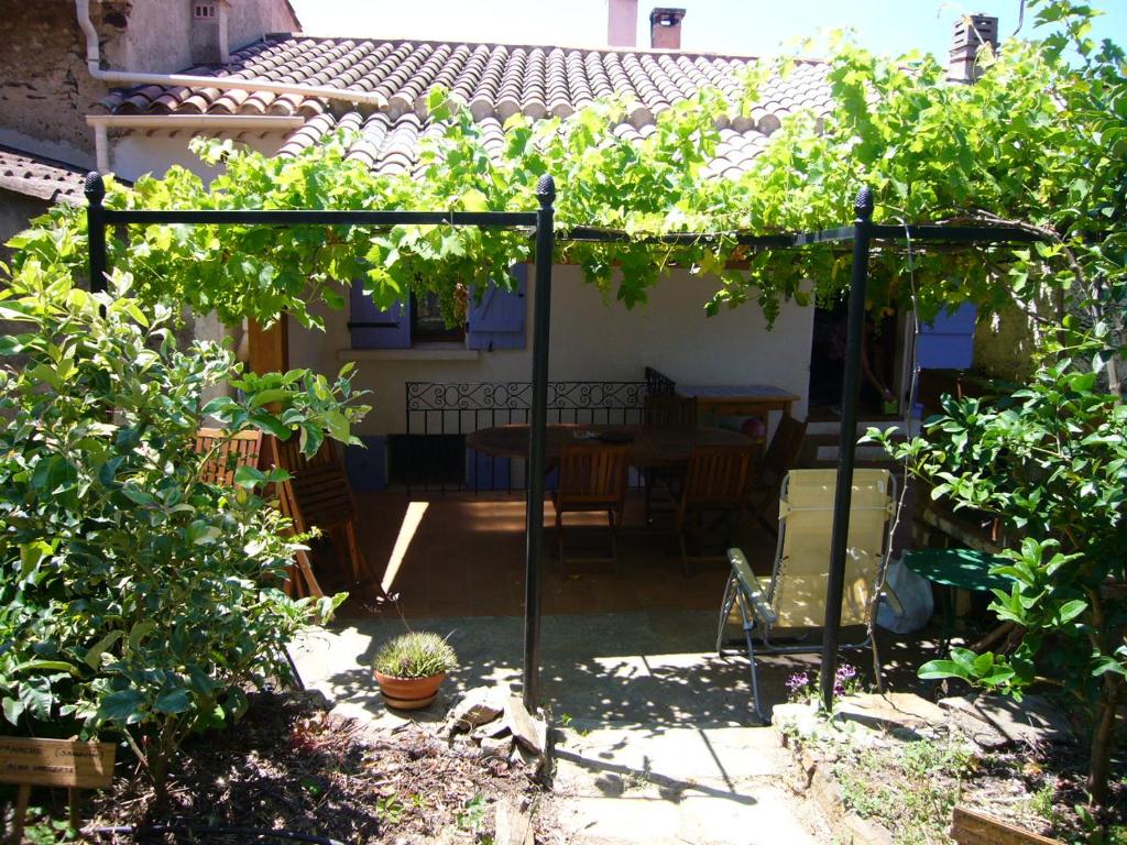 un jardín con una pérgola con una mesa y algunas vides en Maison de charme près de la mer en Bormes-les-Mimosas