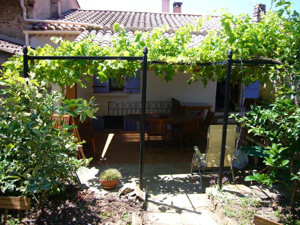 einen Garten mit einer Pergola mit einem Tisch und einigen Reben in der Unterkunft Maison de charme près de la mer in Bormes-les-Mimosas