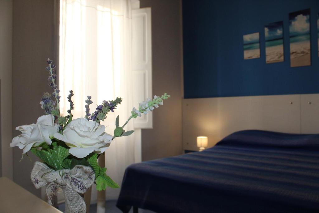 a vase of flowers in a bedroom with a bed at Appartamento Stella del mare in Trapani