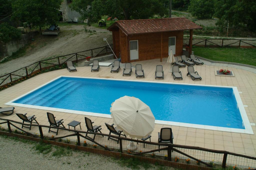 a swimming pool with chairs and an umbrella at Agriturismo Casa Castellini in Garbagna