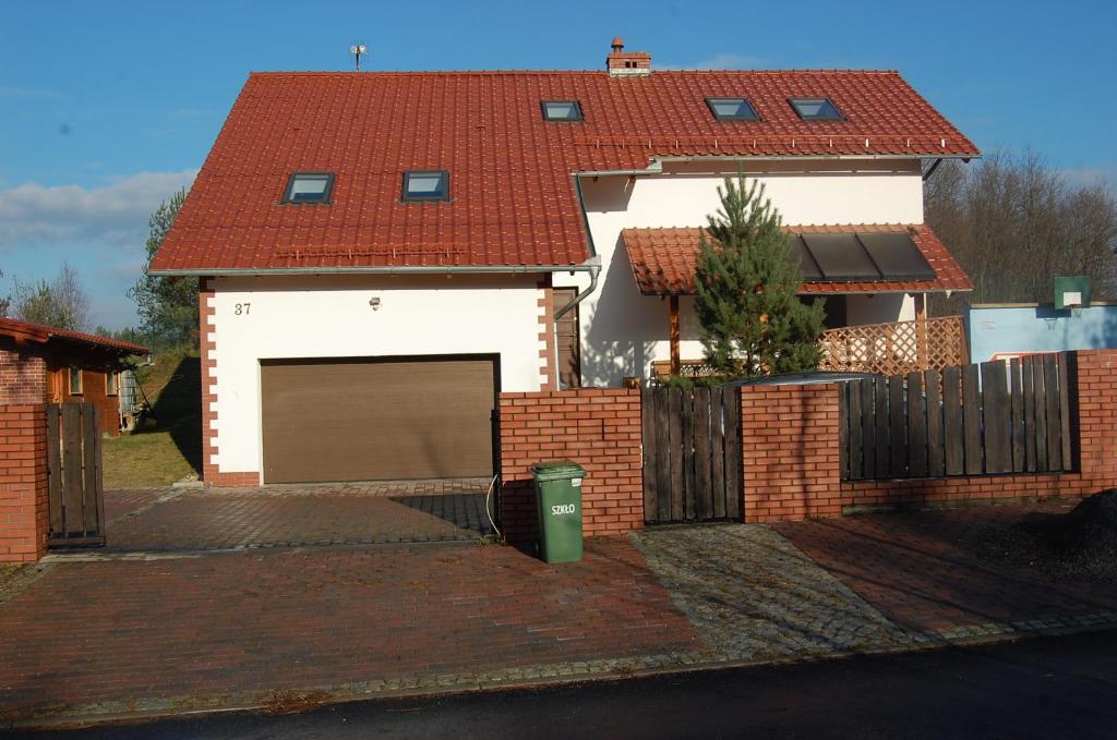 uma casa branca com uma cerca de tijolos e uma garagem em Tenis Pod Sosnami em Osieczów