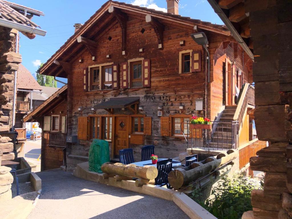 a large wooden house with a porch and stairs at Appartement "Le Ver Luisant" à Saint-Martin, Val d'Hérens, Valais in Saint-Martin