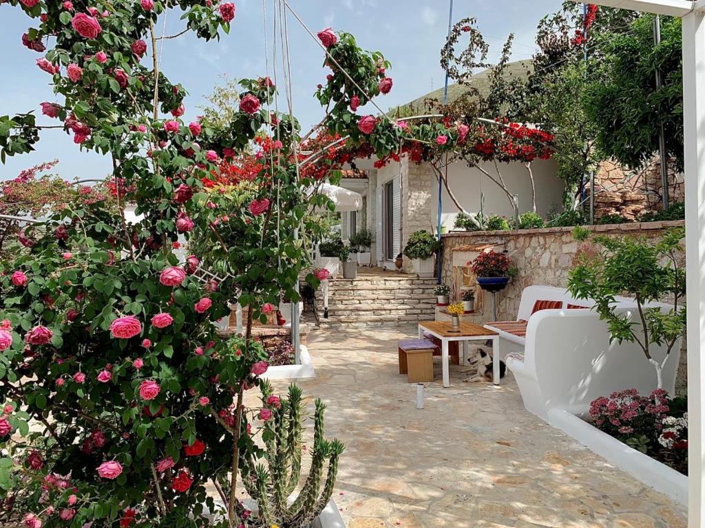 einen Garten mit rosa Rosen und ein Haus in der Unterkunft Holiday Home Ali in Piqeras