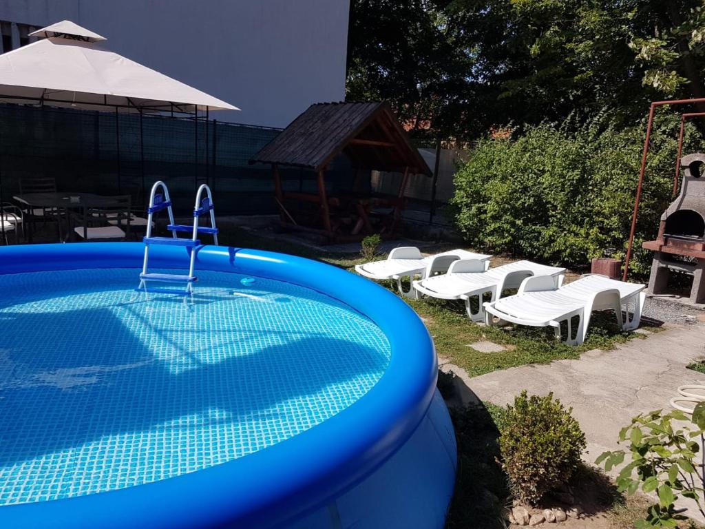 uma grande piscina azul com cadeiras brancas e um guarda-sol em CASA AMBROZIA em Eforie Sud