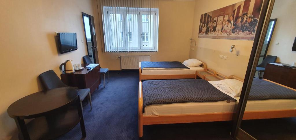 um quarto com 3 camas, uma secretária e um computador em Pentagos em Poznań