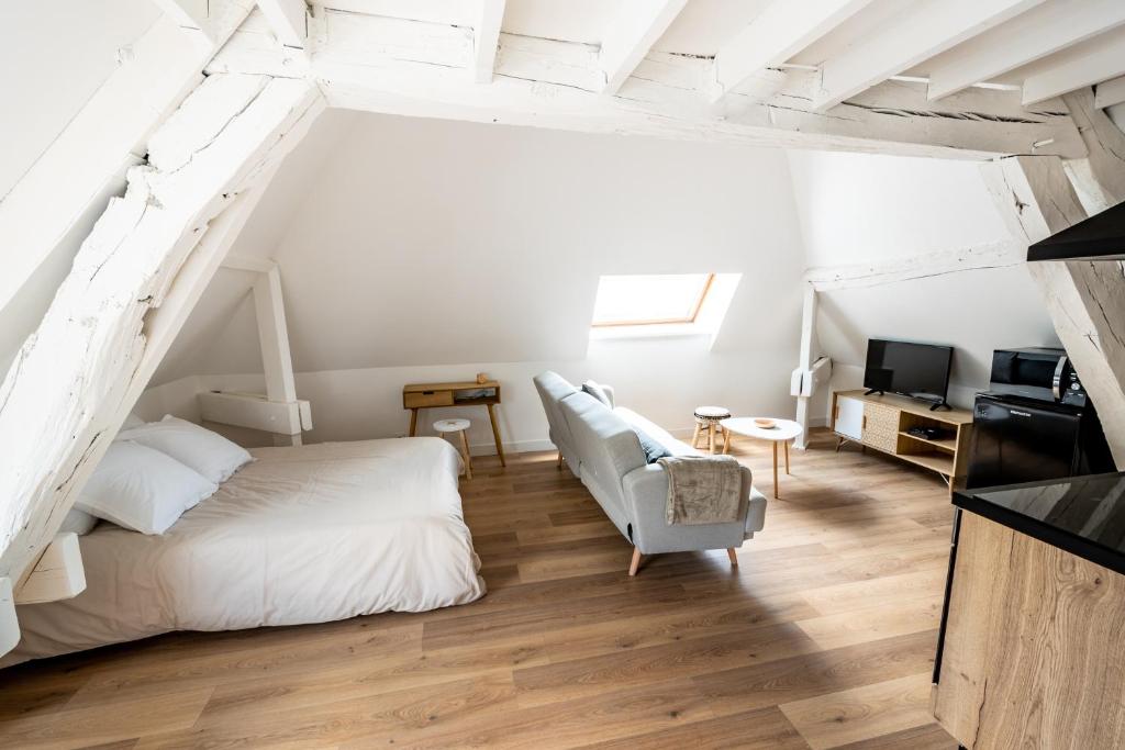 een witte slaapkamer met een bed en een stoel bij Le Relais De La Ravine in Vernon