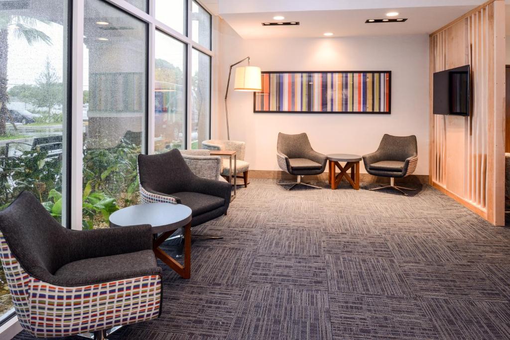a waiting room with chairs and a tv and windows at Holiday Inn Express & Suites - St. Petersburg - Madeira Beach, an IHG Hotel in St. Petersburg