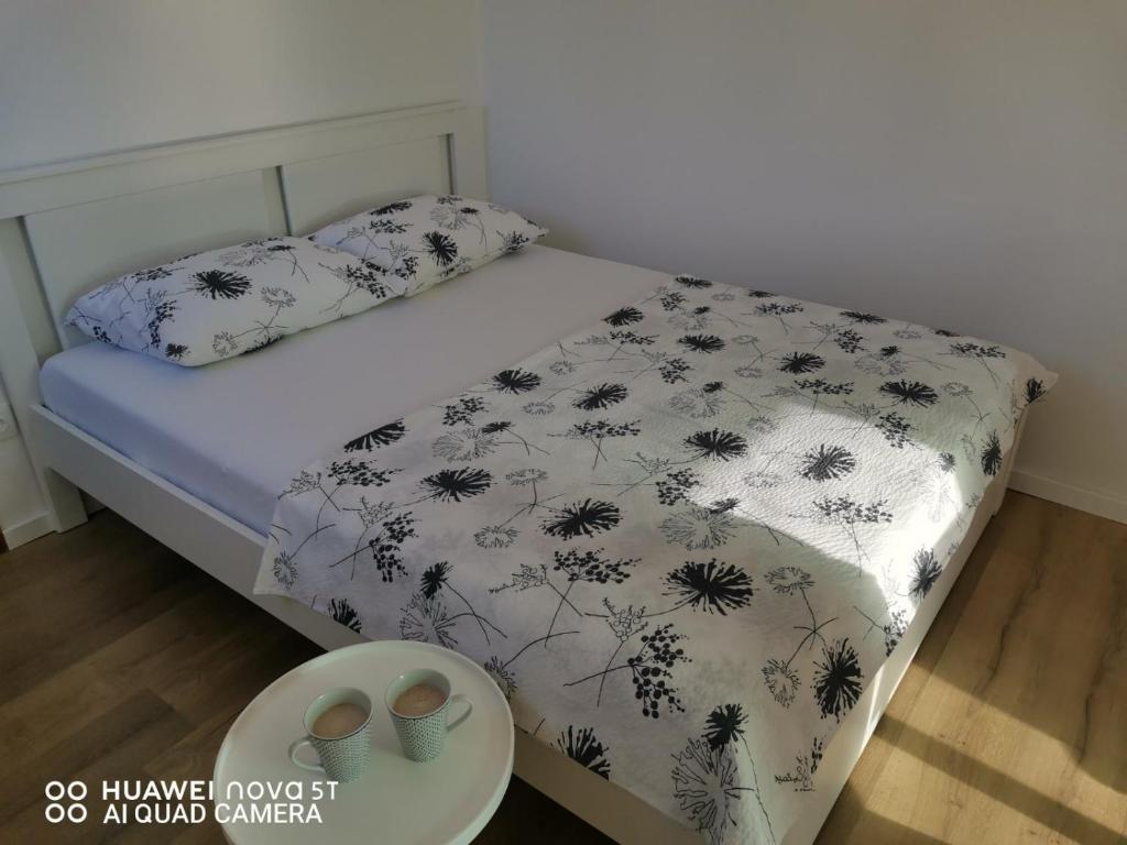 a bed with a black and white comforter and two shoes at Apartments Natalija & Ante in Grebaštica