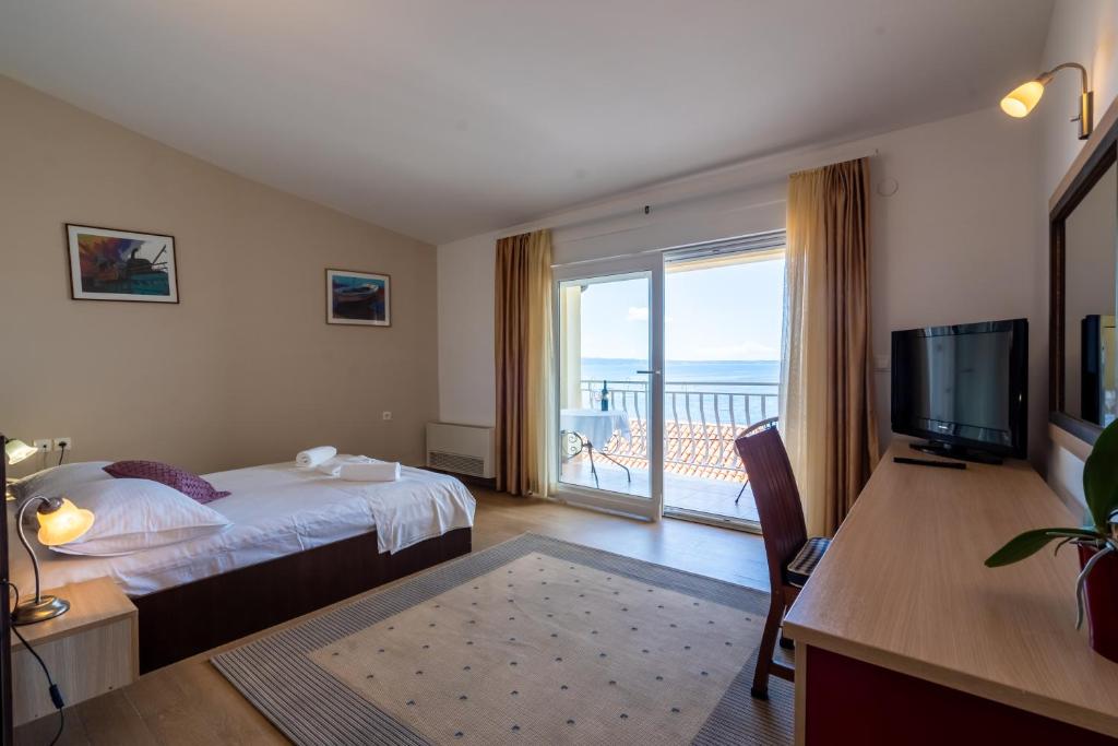 a hotel room with a bed and a television and a balcony at Pansion Epetium in Split