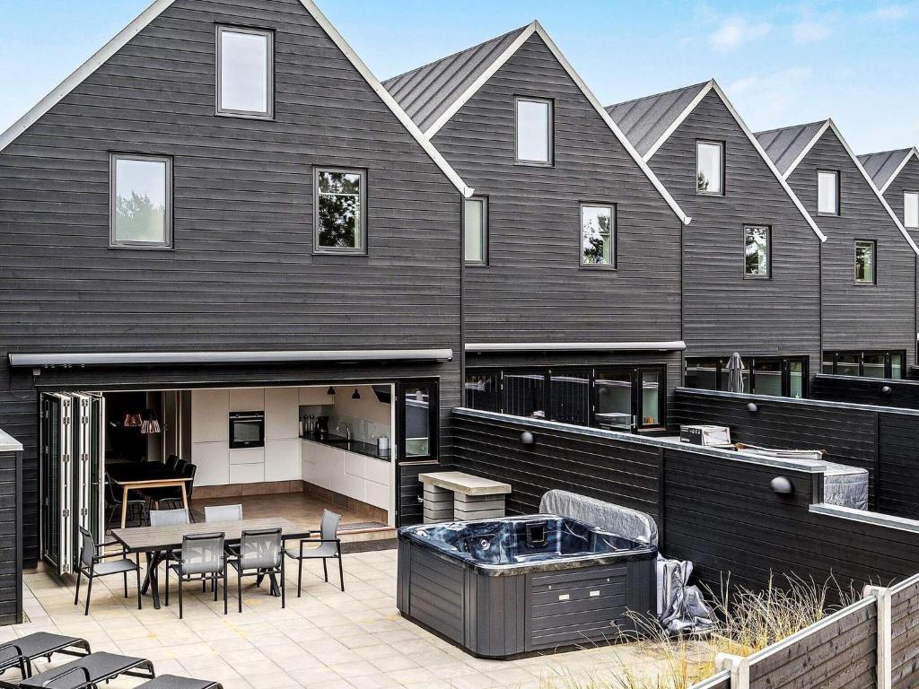 uma grande casa preta com uma banheira de hidromassagem em 8 person holiday home in Bl vand em Blåvand