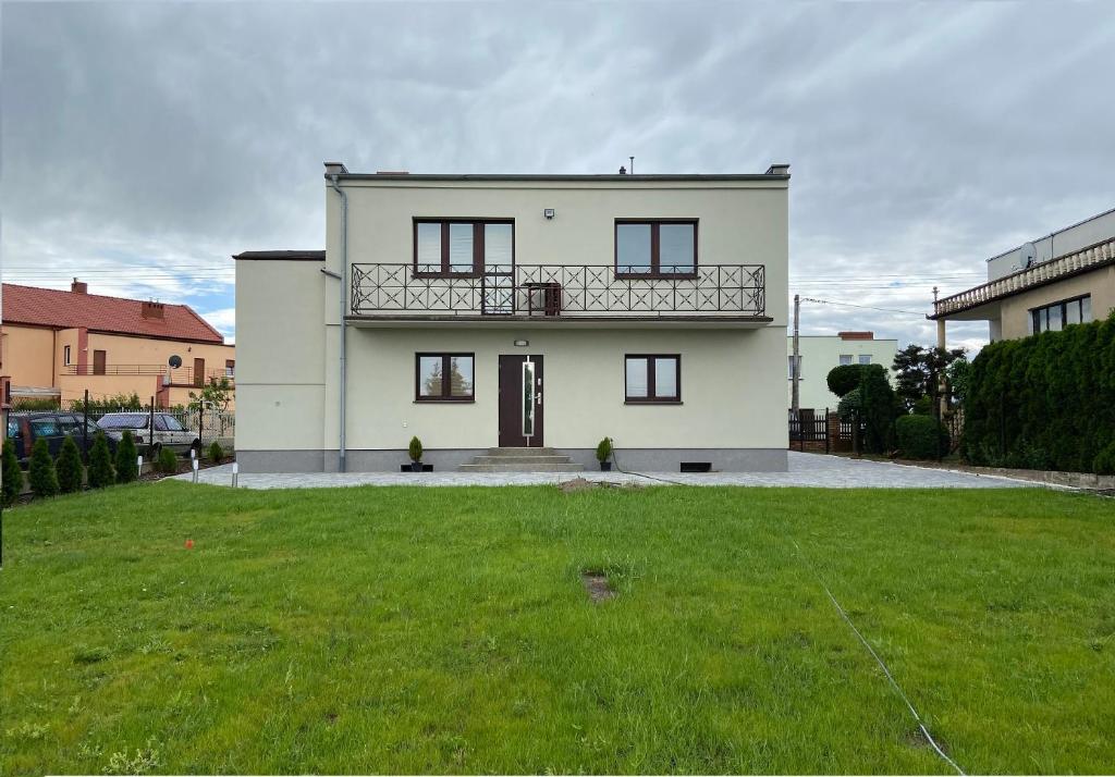 Biały dom z balkonem na dziedzińcu w obiekcie Apartamenty Starowiejska w Gnieźnie