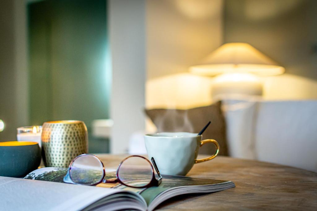 un libro abierto con gafas y una taza sobre una mesa en Onder de Linde B&B en Valkenburg