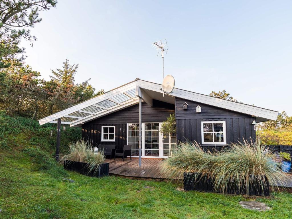 a black tiny house with a large deck at Holiday home Hvide Sande XCIII in Bjerregård
