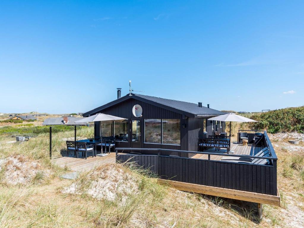 une maison sur la plage avec une terrasse, des chaises et des parasols dans l'établissement Holiday home Hvide Sande XCVI, à Havrvig