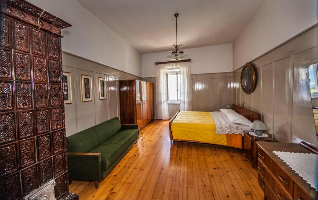 1 dormitorio con 1 cama y 1 sofá verde en Casa Alice, en Malosco